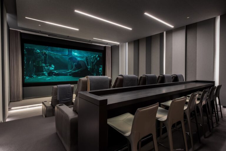 Custom home theater with leather stadium seats, acoustic paneling and a large theater screen.