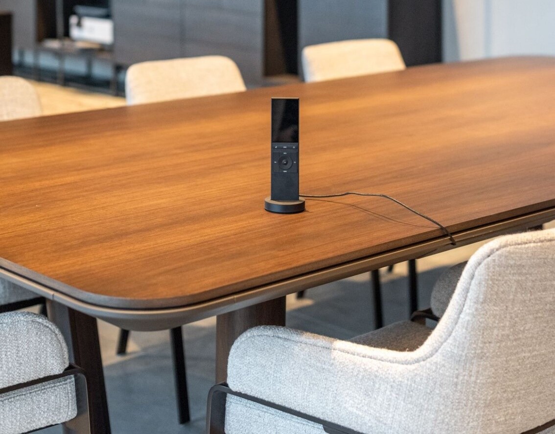 A home automation remote control charging on a table.