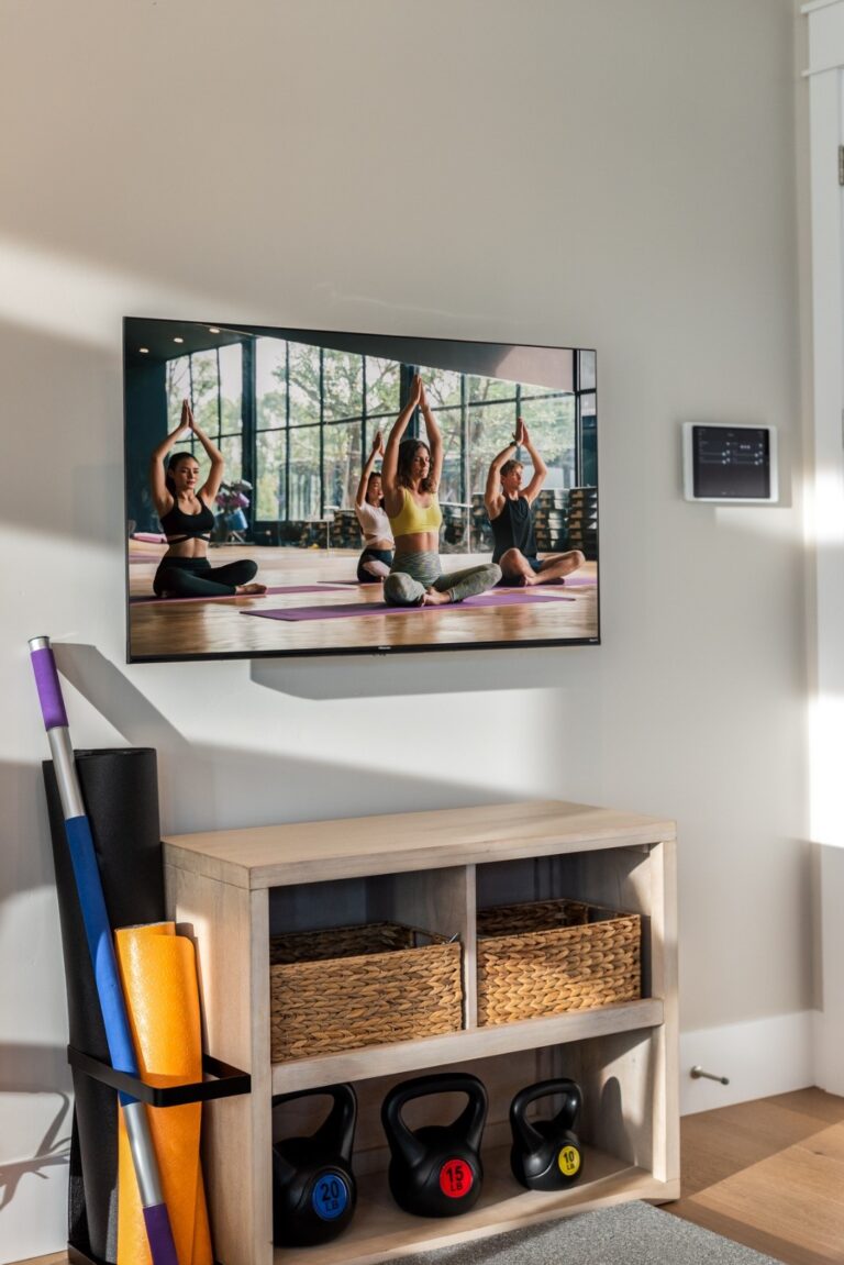 A home gym with a home automation panel and a TV mounted on the wall.