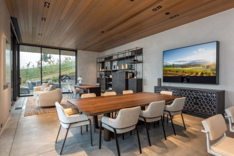 A dining room with a large TV mounted on the wall.