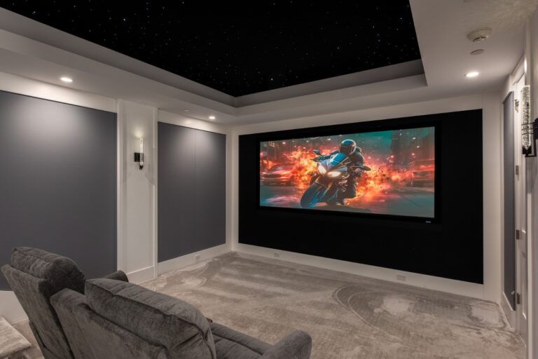 A home theater screen on the wall with large chairs in front.