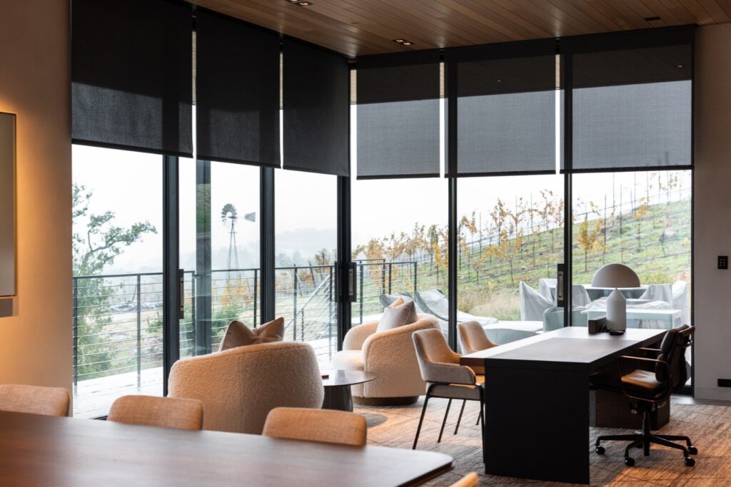 Six automatic blinds are lowered inside of a home’s dining room.