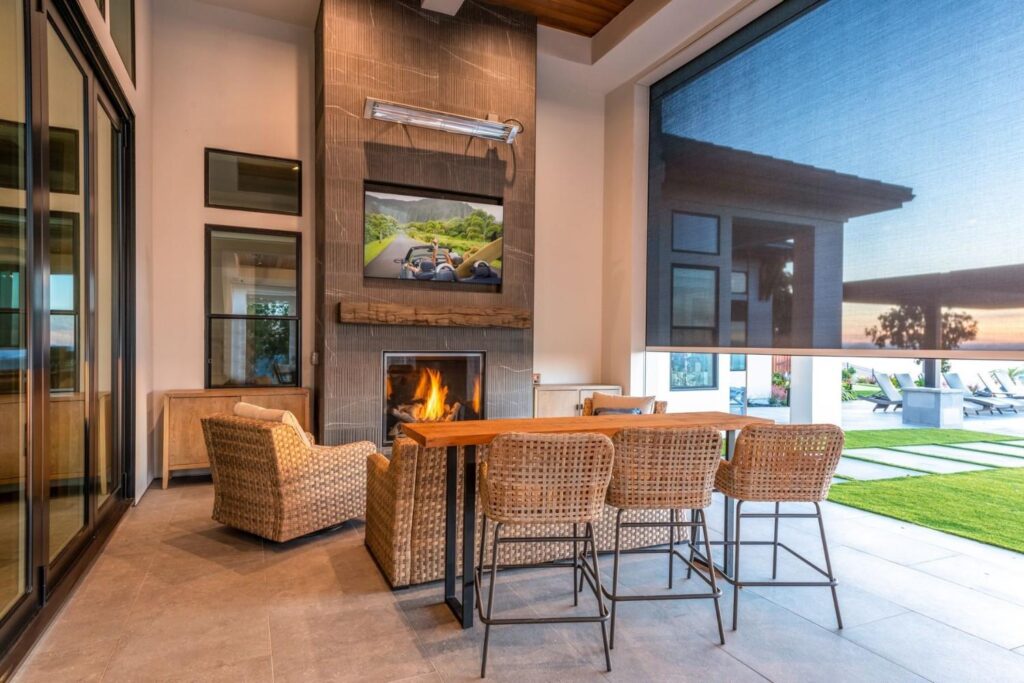 A bench table on a patio with motorized blinds closing.