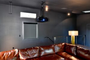 A media room with a video projector installed on the ceiling.