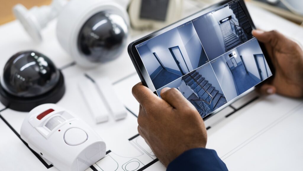 A person holds a screen showing security camera angles.