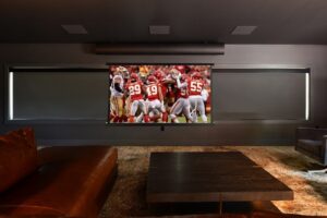 A view of the media room with motorized shades and projector screen down.